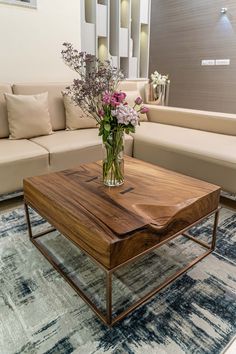 a living room with couches, tables and flowers in vases on the coffee table
